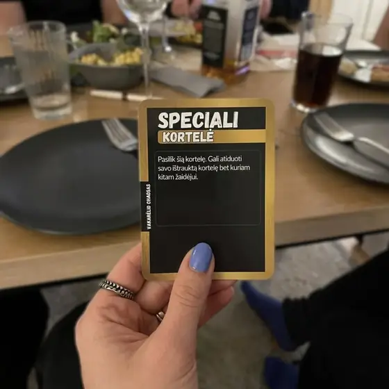 Vakarienės stalas su kortele rankoje